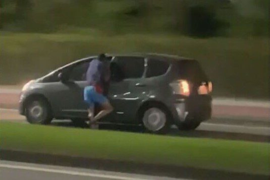 Pendurado na janela. Imagens circulam nas redes sociais de um homem pendurado na janela de um carro em movimento na Barra da Tijuca, no RJ